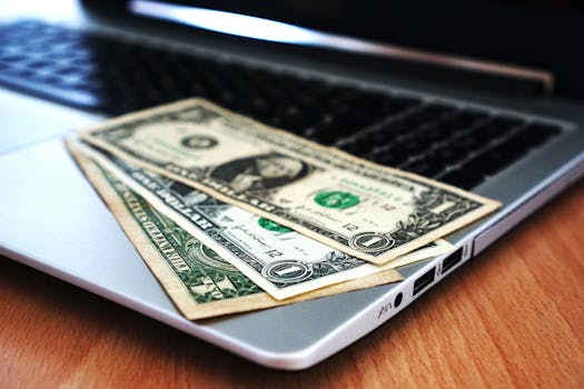 Close-up of US dollar bills placed on a laptop symbolizing digital finance and economy.make money online at home